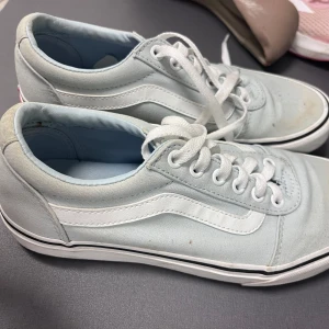 Ljusblåa Vans sneakers med vit sula - Säljer ett par klassiska Vans sneakers i ljusblå canvas med vit sula och vit sidostrip. Skorna har snörning och den ikoniska bruna gummisulan undertill. Perfekta för en avslappnad och cool stil.