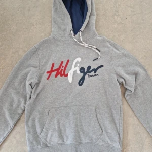 Grå hoodie Tommy Hilfiger Denim S - Snygg grå hoodie från Tommy Hilfiger i storlek S men skulle eventuellt funka för liten M. Bra kvalite 8/10. Skriv vid funderingar. Pris 399kr.