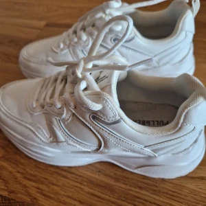 Vita sneakers från Pull&Bear - Chunky vita sneakers från Pull&Bear med snygga detaljer och tjock sula. Skorna har snörning och är tillverkade i syntetmaterial med meshpartier för extra komfort. Perfekta för dig som gillar en clean och sportig look.