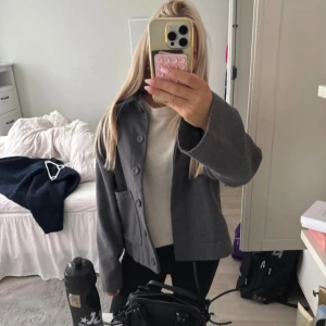 Grå overshirt från AWARE XS - Snygg grå overshirt från AWARE i storlek XS. Jackan har en rak passform, stora fickor framtill och stängs med knappar. Perfekt att slänga över en hoodie eller t-shirt för en chill look. Materialet känns mjukt och passar bra till höst och vår.