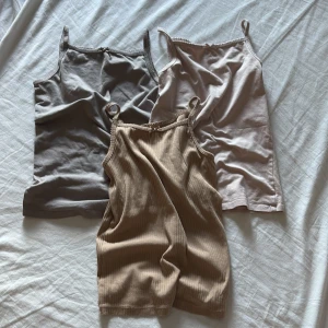 3-pack baslinnen i neutrala färger - Tre stilrena linnen i grått, beige och ljusrosa. Alla har smala axelband och en enkel, rak passform. Ett av linnena är ribbat för extra textur och de andra två är släta. Perfekta att matcha med jeans eller shorts för en clean look.