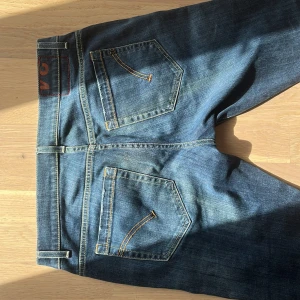 Blå jeans från Dondup - Snygga blå jeans från Dondup med klassisk femficksdesign och kontrastsömmar. Jeansen har raka ben och normal passform, tillverkade i slitstarkt denim med coola detaljer som röd söm och logga på bakfickan. Perfekta för en avslappnad och trendig look.