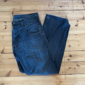 Svarta Lee jeans straight fit - Säljer ett par klassiska svarta jeans från Lee med raka ben och normal passform. Jeansen har fem fickor, snygga slitningar och Lee-logga på bakfickan. Perfekta för dig som gillar en tidlös look och vill ha ett par jeans som funkar till allt.