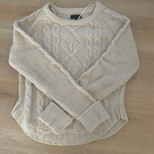 Beige stickad tröja från Vero Moda - Beige stickad tröja från Vero Moda i storlek XS💕Tröjan har ett snyggt flätmönster framtill och längs ärmarna, rund halsringning och ribbade muddar!🥰