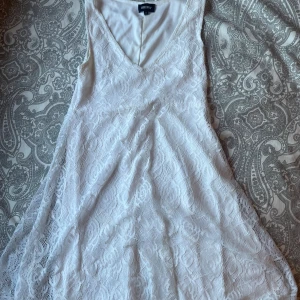 Vit spetsklänning från Bubbleroom - Supersöt vit klänning från Bubbleroom i storlek S. Klänningen har v-ringad hals, ärmlös design och är täckt av romantisk spets med blommigt mönster. Den är kort och har en lätt utsvängd form som ger en fin siluett. Perfekt för sommarens alla tillfällen! Lite flackar men annars fin.