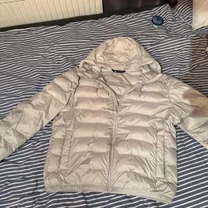 Vitt jacka  från Zara med huva - Säljer en vitt pufferjacka från Zara i storlek L. Jackan har huva, dragkedja framtill och två fickor på sidorna. Perfekt för kyliga dagar och enkel att matcha med olika outfits. Jackan är lätt och har en stilren look.