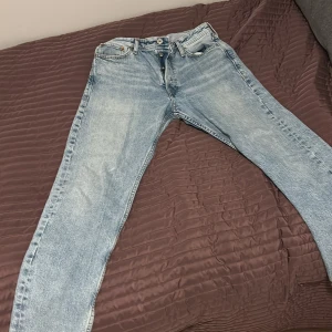 Ljusblå jeans från Jack & Jones 30/30 - Säljer ett par ljusblå jeans från Jack & Jones i klassisk straight fit. Jeansen har fem fickor, knappgylf och snyggt tvättad denim. Perfekta för dig som gillar en avslappnad och tidlös look. Märke: Jack & Jones, storlek 30/30.
