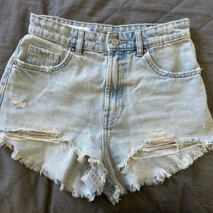 Ljusblå jeansshorts - Snygga ljusblå jeansshorts med hög midja och slitna detaljer. Klassisk femficksmodell med knapp och dragkedja framtill. Helt nya och oanvända!!🩵🩵🩵