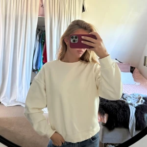 Krämvit  sweatshirt - Säljer en enkel och stilren krämvit sweatshirt med rund hals och långa ärmar. Tröjan har en oversized passform. Ribbade muddar vid ärmslut och nederkant.