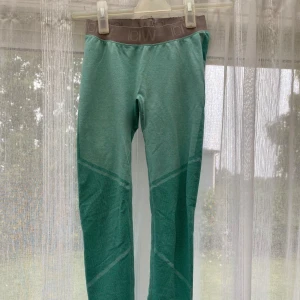 Gröna leggings från ICANIWILL - Snygga gröna leggings från ICANIWILL med bred resår i midjan och diskret logga. De har en tight passform och är perfekta för träning eller chill. Materialet är stretchigt och andas bra, vilket gör dem riktigt bekväma.