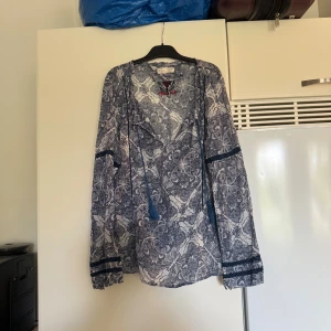 Odd Molly blus  - Otroligt vacker blus o en ljusblå bottenfärg. Den har ett superfint marinblått detaljerat mönster. Med fina marinblåa spets detaljer. Storlek 2 som enligt deras storleksguide motsvarar en storlek M. Fint skick, men jag tyckte jag hittade ett hål i blusen. Men nu hittar jag inte det. Annars fint skick. 
