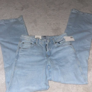 Bootcut jeans i ljusblå denim från 157 - Säljer ett par snygga lågmidjade  bootcut jeans från 157 i ljusblå denim. Modellen heter 90's Boot och har klassiska femficksdetaljer, dragkedja och knäppning fram samt coola fickor med lock bak. Perfekta för dig som gillar retrovibbar och relaxed fit.