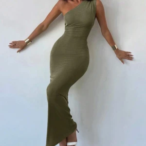 Olivgrön långklänning med öppen rygg - Säljer en olivgrön långklänning med tight passform och snygg omlott-detalj i ryggen som knyts med en stor rosett. Klänningen är ärmlös och har en öppen rygg som ger en riktigt cool look. Materialet känns mjukt och stretchigt, perfekt för dig som gillar att sticka ut.