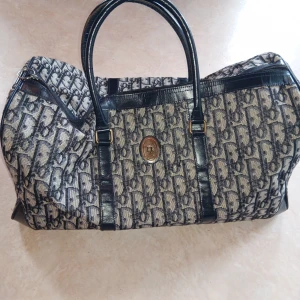 Dior weekendbag i blått monogram - Säljer en stor och rymlig weekendbag från Dior med klassiskt blått monogrammönster och svarta skinnhandtag. Väskan har detaljer i mörkblått skinn, dragkedja upptill och 2 praktiska fickor på sidan. Perfekt för resor eller när du behöver extra plats. Kan gå ner i pris vid smidig affär. Finns i Trollhättan / Göteborg området 