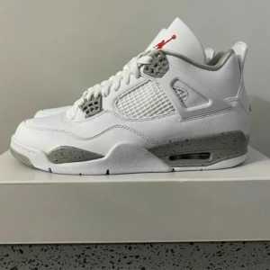Nike Air Jordan 4 White Oreo sneakers - Nike Air Jordan 4 White Oreo sneakers med vit ovandel i skinn, meshpaneler och grå detaljer med svart stänkmönster på sulan. Klassisk siluett med snörning, synlig Air-enhet och röd Jumpman-logga på plösen. Perfekt för dig som gillar streetstyle och ikoniska sneakers.