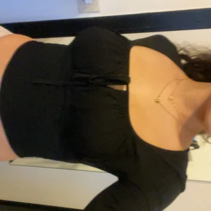 Svart croppad topp med knyt XS - Säljer en svart långärmad topp med croppad passform och snygg knytning framtill. Toppen har fyrkantig urringning och sitter tight mot kroppen