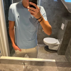 Ljusblå t-shirt från Ralph Lauren - Snygg ljusblå Ralph lauren t-shirt i riktigt bra skick. Tyvärr har denna T-shirt blivit liten på mig och därför säljer jag nu denna. Köptes ny för 1000kr. Jag är 188cm och bär storlek S på bilden. Skriv vid funderingar:)