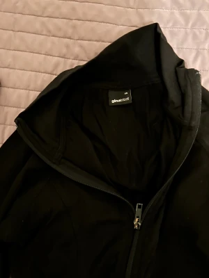 Svart vindjacka från Gina Tricot XS - Svart vindjacka från Gina Tricot i storlek XS. Jackan har en hög krage, hel dragkedja framtill och långärmade smala ärmar. Materialet är mjukt och lätt, perfekt för svala dagar. Enkel och stilren design som funkar till många outfits.