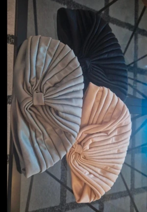 Turbanmössor i svart, grå och beige  - Tre snygga turbanmössor i svart, grå och beige. De har en cool veckad design med knut framtill som ger en unik look. Perfekt för dig som vill sticka ut med din stil. Mjukt material som sitter skönt på huvudet.