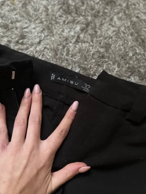 Svarta kostymbyxor från Amisu - Svarta kostymbyxor från Amisu i storlek 32. Klassisk rak passform med bälteshällor och diskret dragkedja framtill. Snygga till en enkel topp eller skjorta, perfekta för en clean och stilren look.