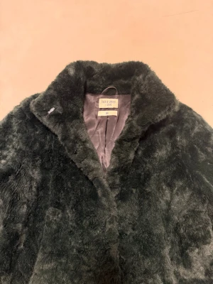 Mörkgrön pälsjacka Tiger of Sweden - Säljer en mörkgrön fuskpälsjacka från Tiger of Sweden Jeans i storlek Small. Jackan har en fluffig och mjuk yta, hög krage och två sidofickor. Perfekt för dig som vill ha en snygg och varm look under höst och vinter.