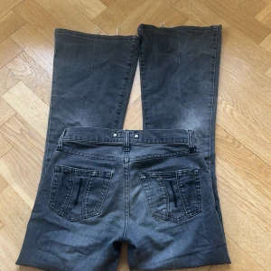 Bootcut jeans från Fornarina Area - Snygga bootcut jeans från Fornarina Area i mörkgrå tvätt med slitningar och klassiska fem fickor. Jeansen har låg midja, vida ben och råa kanter nedtill för en cool vibe. Materialet är jeans med en mjuk känsla och passformen är loose. Passar alla er tjejer som vill känner er extra snygga i vinter. Funkar för både storlek 32 och 34.