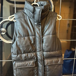 Svart väst - Helt ny väst utan prislapp, aldrig använd. Västen är i vattenavstötande material. Storlek 150, men jag som vanligtvis har S i kläder kan även ha denna.