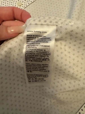 Vit mönstrad skjorta Tommy Hilfiger - Vit skjorta från Tommy Hilfiger i regular fit med små mörkblå mönster över hela tyget. Klassisk krage, knappar framtill och diskret logga broderad på bröstet. Skjortan är gjord i mjuk bomull och har en fräsch, modern look som sticker ut.