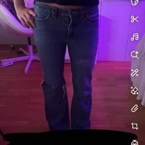 Jeans med hål - Säljer ett par blå jeans från cecil med bootcut/straight passform och låg midja. Jeansen har klassiska fickor och slitning med hål på ena knät för en cool, avslappnad vibe. Materialet är robust denim och färgen är mörkblå med lätt tvättad look.