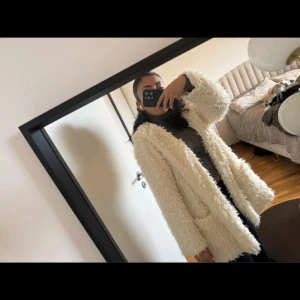 Vit teddyjacka med huva från Zanzea - Fluffig och oversized teddyjacka från Zanzea i vit färg. Jackan har huva, stora fickor framtill och är helfodrad med glansigt tyg. Perfekt för dig som gillar mysiga och trendiga plagg med chill vibe.