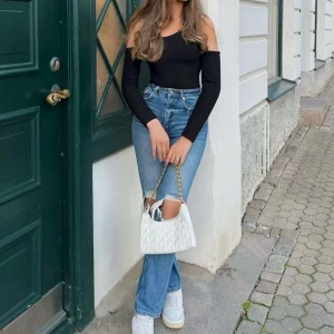 Blå jeans med hål på knäna - Snygga blå jeans med hög midja och raka ben. Jeansen har slitna detaljer och stora hål på knäna för en trendig look. Perfekta att matcha med sneakers och crop top för en cool streetstyle.