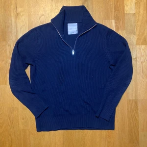 stickad half zip från Jack & Jones - Snygg marinblå stickad tröja från Jack & Jones med ribbad struktur och half zip-dragkedja i halsen. Tröjan har lång ärm och hög krage, perfekt för dig som gillar stilren och enkel design. Passar dig som vill ha en chill och klassisk look.
