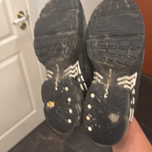 Nike Air Max Plus Tuned Air svart/vit - Nike Air Max Plus Tuned Air sneakers i svart och grått med vita detaljer. Skorna har en sportig design med synlig Air Max-dämpning, snörning och mesh-överdel. Swoosh-logga på sidan och Tuned Air-detaljer på sulan. Perfekta för dig som gillar streetwear och komfort.