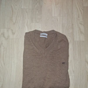 Beige v-ringad tröja Pedro del Hierro - Snygg beige v-ringad tröja från Pedro del Hierro med diskret broderad logga på bröstet. Tillverkad i en mjuk blandning av ull och kashmir som känns lyxig och skön mot huden. Perfekt för dig som gillar stilrena och klassiska plagg. Hör gärna av er vid frågor eller prisförslag‼️