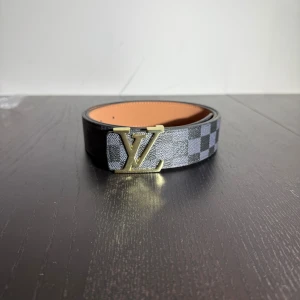 Bälte  - Ett svart rutigt bälte med en unik guldig logga 