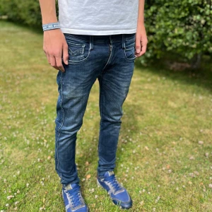 Replay Anbass hyperflex jeans blå, stl 30 - Säljer ett par snygga Replay Anbass hyperflex jeans i mörkblå tvätt med slitningar och kontrastsömmar. Modellen är slim fit med normal midja och klassiska fem fickor. Jeansen är tillverkade i bomull med stretch för extra komfort.