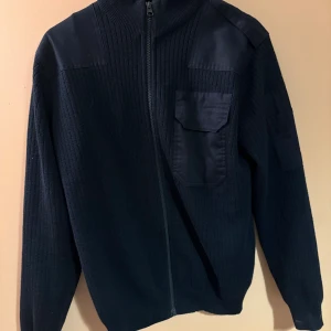 Stickad kofta - Svart stickad cardigan från Ted Bernhardtz med hel dragkedja, ribbad struktur och förstärkta partier på axlar och armbågar. Bröstficka med lock och hög krage ger en clean och stilren look. Perfekt för lager-på-lager under kyliga dagar. Nypris ca 2100. Skick 10/10 ☺️