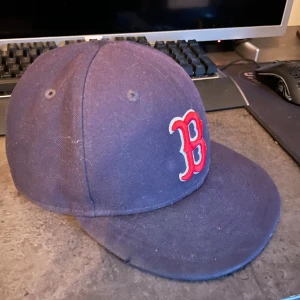 Boston Red Sox keps New Era 59FIFTY - Snygg mörkblå Boston Red Sox keps från New Era, modell 59FIFTY. Klassisk basebollstil med röd och vit broderad B-logga framtill och New Era-logga på sidan. Perfekt för dig som gillar sportig streetwear och vill representera ditt lag.