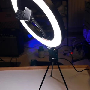 Ring Light med stativ och mobilhållare - Ring Light med justerbar ljusstyrka och färgtemperatur, stativ och flexibel mobilhållare. Perfekt för streaming, foto eller video. USB-anslutning och fjärrkontroll på sladden. Mycket gott skick, inga synliga defekter eller slitage.