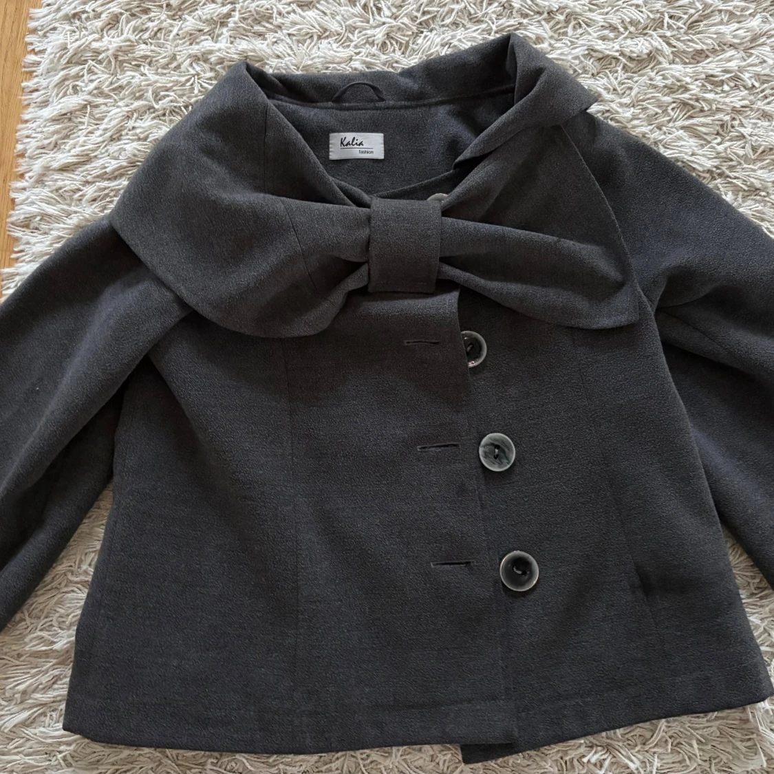 Mörkgrå kappa med rosett från Kalia