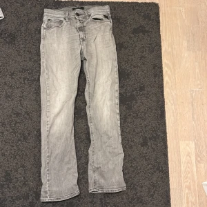 Replay Thad grå jeans straight fit - Säljer ett par Replay Thad jeans i snyggt grått med tvättad look. Klassisk femficksmodell med raka ben och svarta detaljer vid fickorna. Jeansen har normal passform och är tillverkade i mjukt jeanstyg som är skönt att bära hela dagen.