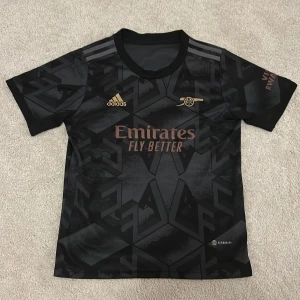 Arsenal fotbollströja - Snygg svart Arsenal fotbollströja från adidads. Tillverkad i lätt och ventilerande material, perfekt för match eller träning. Tröjan är i storlek 158cm.