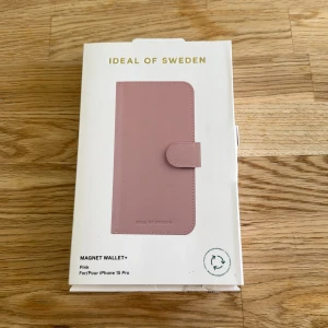Magnet Wallet+ Pink för iPhone 15 Pro - Elegant Magnet Wallet+ i rosa från Ideal of Sweden, anpassad för iPhone 15 Pro. Plånboksfodralet har flera kortfack, magnetisk stängning och avtagbart svart skal. Djurfritt material. Produkten är i nyskick och är ej använd, endast förpackningen har mindre slitage.