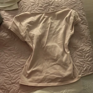 Ljusbeige kortärmad topp med djup rygg - Säljer en ljusbeige topp med korta ärmar och en snygg djup urringning i ryggen. Toppen har en slim passform och är tillverkad i mjuk bomull, perfekt för dig som gillar stilrena och enkla plagg. Passar dig som vill ha en basic men ändå trendig look.