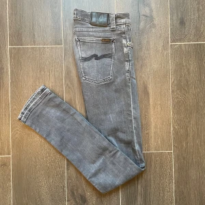 Nudie Jeans Grå - Snygga grå jeans från Nudie, modell Long John. De har en slim fit passform och klassisk femficksdesign med svarta broderade detaljer på bakfickorna. Tillverkade i 98% ekologisk bomull och 2% elastan för extra stretch och komfort. Pris kan diskuteras och om du har några frågor så är det är bara att skriva🙃
