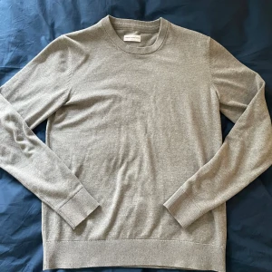 Grå stickad tröja These Glory Days - Snygg grå stickad tröja från These Glory Days i storlek S. Tröjan har rund hals, ribbade muddar och är långärmad. Perfekt för dig som gillar stilrena och enkla plagg med skön passform. Materialet är mjukt och passar bra till lager-på-lager.