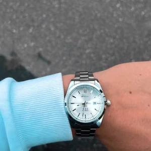 Silverfärgad quartzklocka från Doventi  - Stilren klocka från Doventi med rund urtavla i silver och datumvisning. Quartz-urverk och metallarmband i blankt silver. Snygga svarta index och romerska siffror på urtavlan. Perfekt för dig som gillar klassisk design med modern touch.