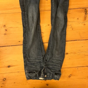 Blå jeansbyxor från Gina Tricot 158 - Snygga blå jeansbyxor från Gina Tricot i storlek 158. Klassisk femficksmodell med bakfickor med lock och knapp, samt resår i midjan för extra komfort. Jeansen har en mörk tvätt med slitningar och kontrastsömmar. Perfekt för dig som gillar en avslappnad stil.