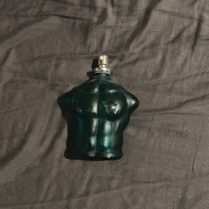Ikonisk blå parfymflaska - Cool parfym i form av en grön manlig torso. Perfekt för dig som vill sticka ut med en klassiker på hyllan. Flaskan är använd men har fortfarande stilren look. Volym och ingredienser syns ej på bilderna. Är mer en hälften kvar i flaskan 