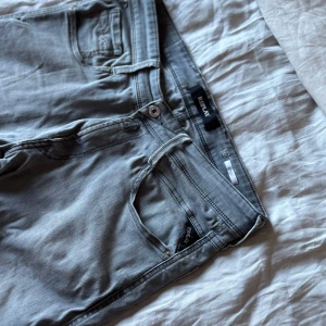 Replay grå jeans slim fit - Snygga grå jeans från Replay med klassisk femficksdesign och smal passform. Jeansen har dragkedjegylf och diskreta Replay-detaljer vid fickorna. Perfekta för dig som gillar en stilren look med lite edge. Skriv för fler frågor eller bilder.
